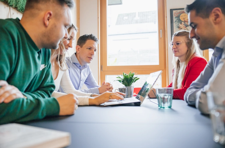 Fünf Personen, drei Männer und zwei Frauen sitzen an einem schwarzen Tisch und diskutieren über die Mindestlohnkommission.