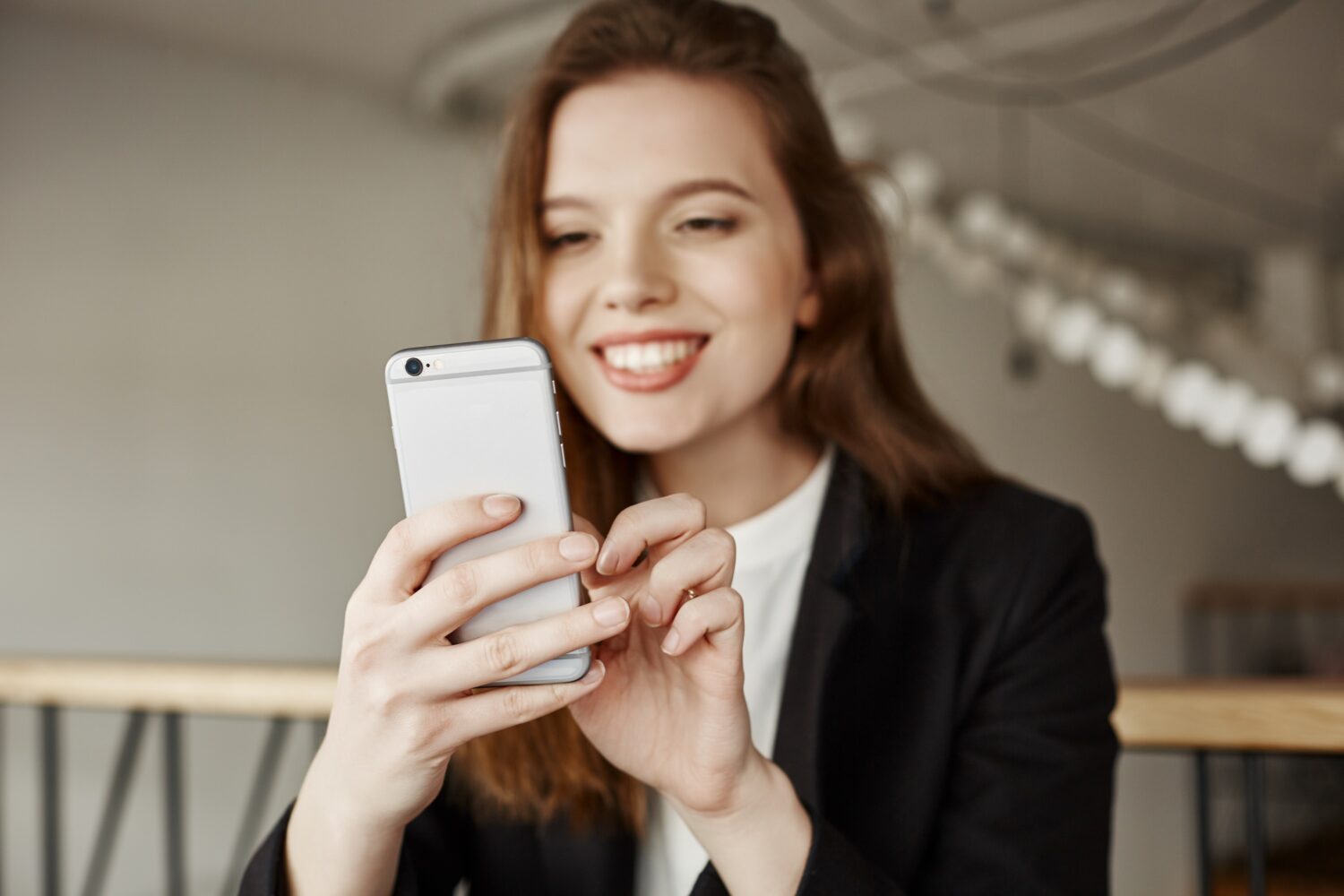 Eine Frau, die Smartphone in den Händen hält und chattet und lächelt.