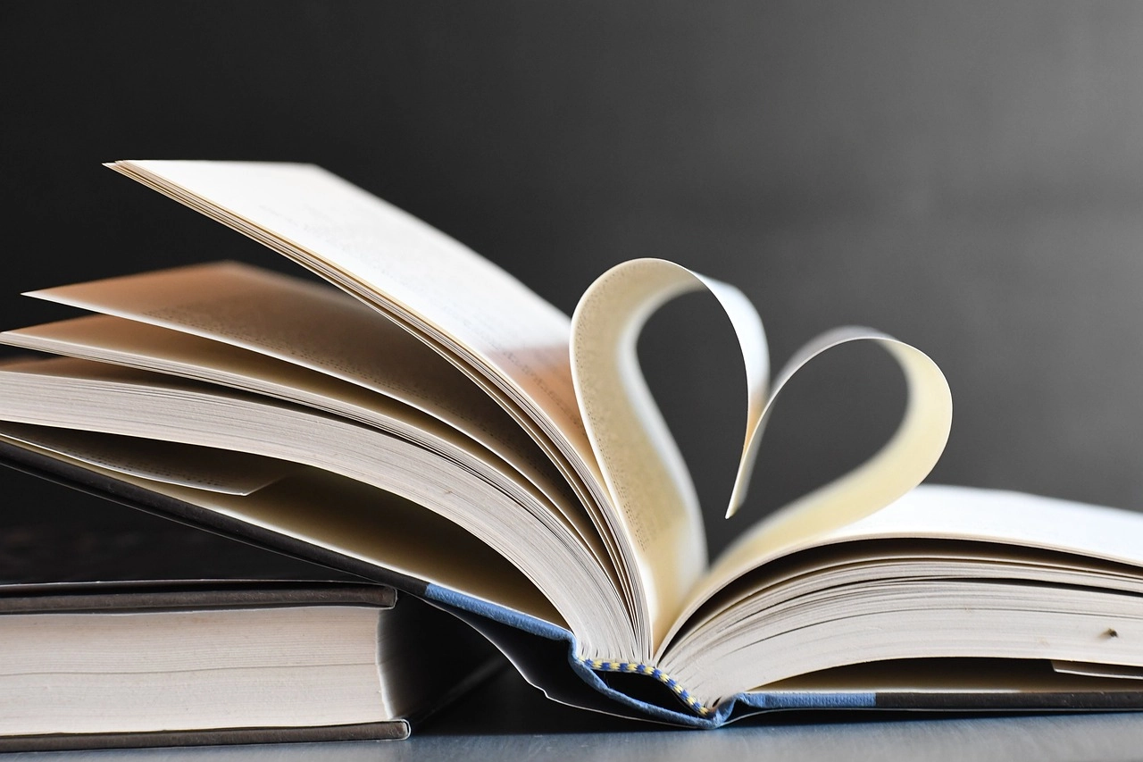 Ein aufgeschlagenes Buch, indem eine Seite zu einem Herz geformt ist. Sinnbildlich für Buchempfehlungen für das Arbeitsleben.