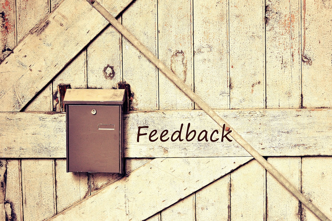 Eine Holzwand an der ein Briefkasten geschraubt ist. Daneben steht das Wort Mitarbeiterfeedback.