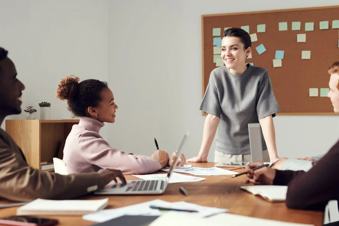 Eine Gruppe von Personen sitzt an einem Tisch. Im Hintergrund sind bunte Post-its mit Notizen zu sehen. Sie sprechen über das Thema Employer Branding