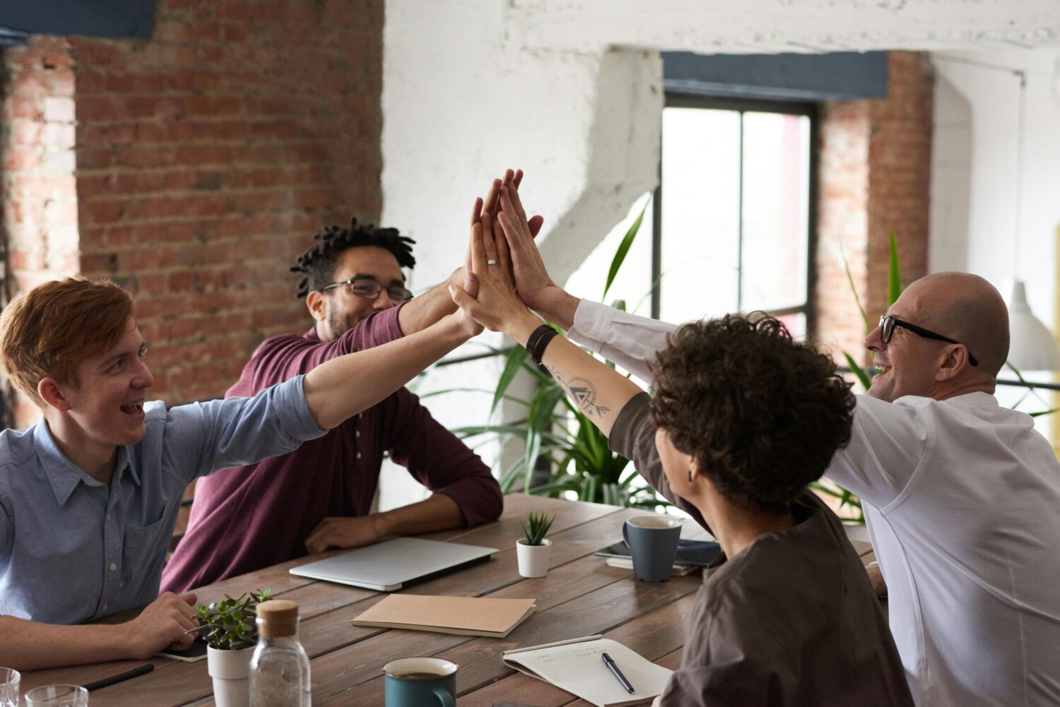 Shared Leadership: Die Zukunft der Teamarbeit, hier dargestellt durch 4 Teammitglieder, die einklatschen mit den Händen
