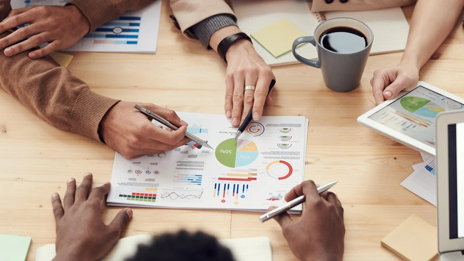 Vergütungsmanagement wird am Tisch von Team diskutiert. In der Mitte Diagramme, Hände zeigen auf verschiedene Themen