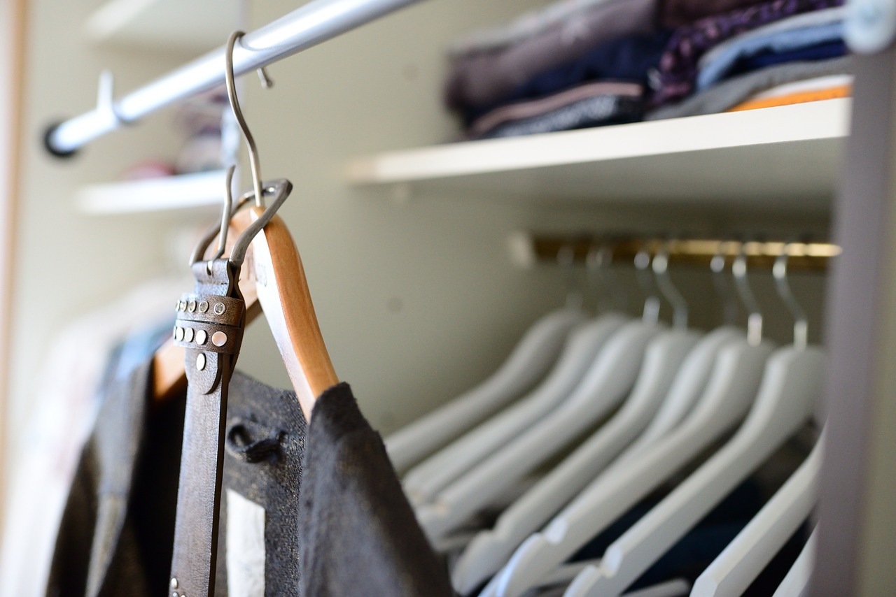 Ein Schrank, in dem Hemden zusammengelegt sind. An der Vorderseite hängt ein Anzug, bereit zum Anziehen. Dresscode Business Formal